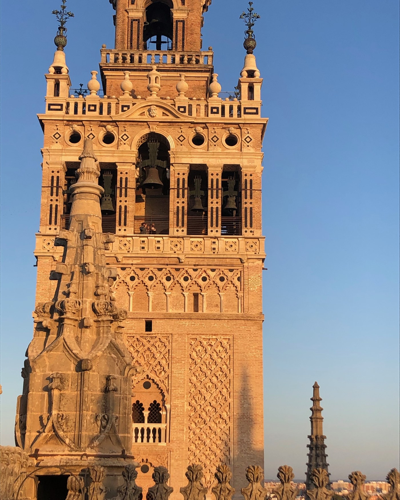 The Giralda bell tower in Seville lit by late afternoon sun against a clear sky